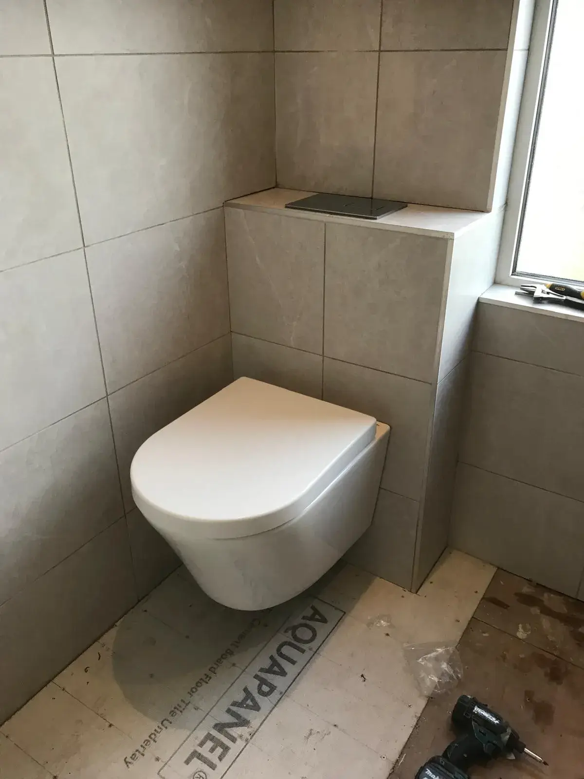 A white toilet sitting in a bathroom next to a window.